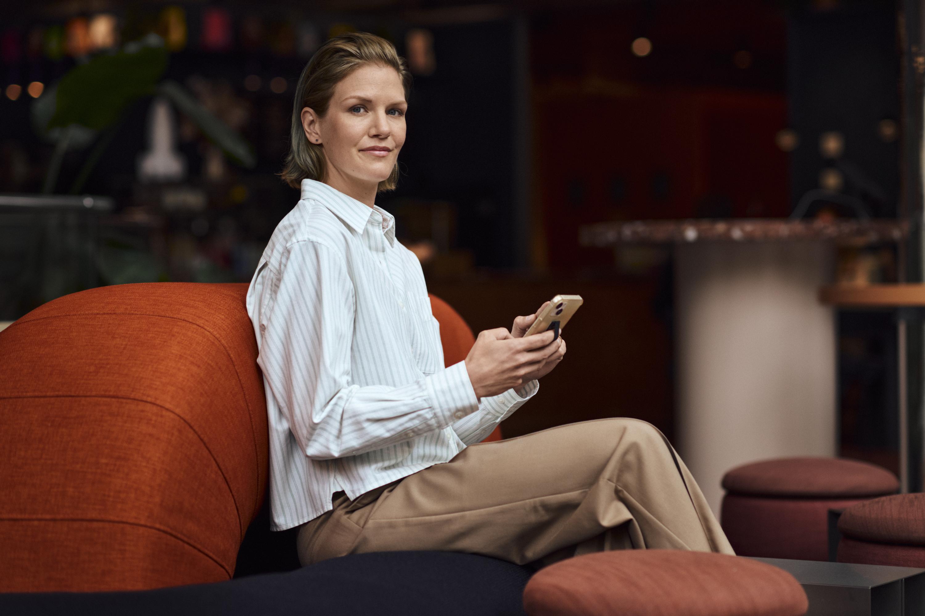 Kvinna sitter i en soffa och tittar på sin mobil