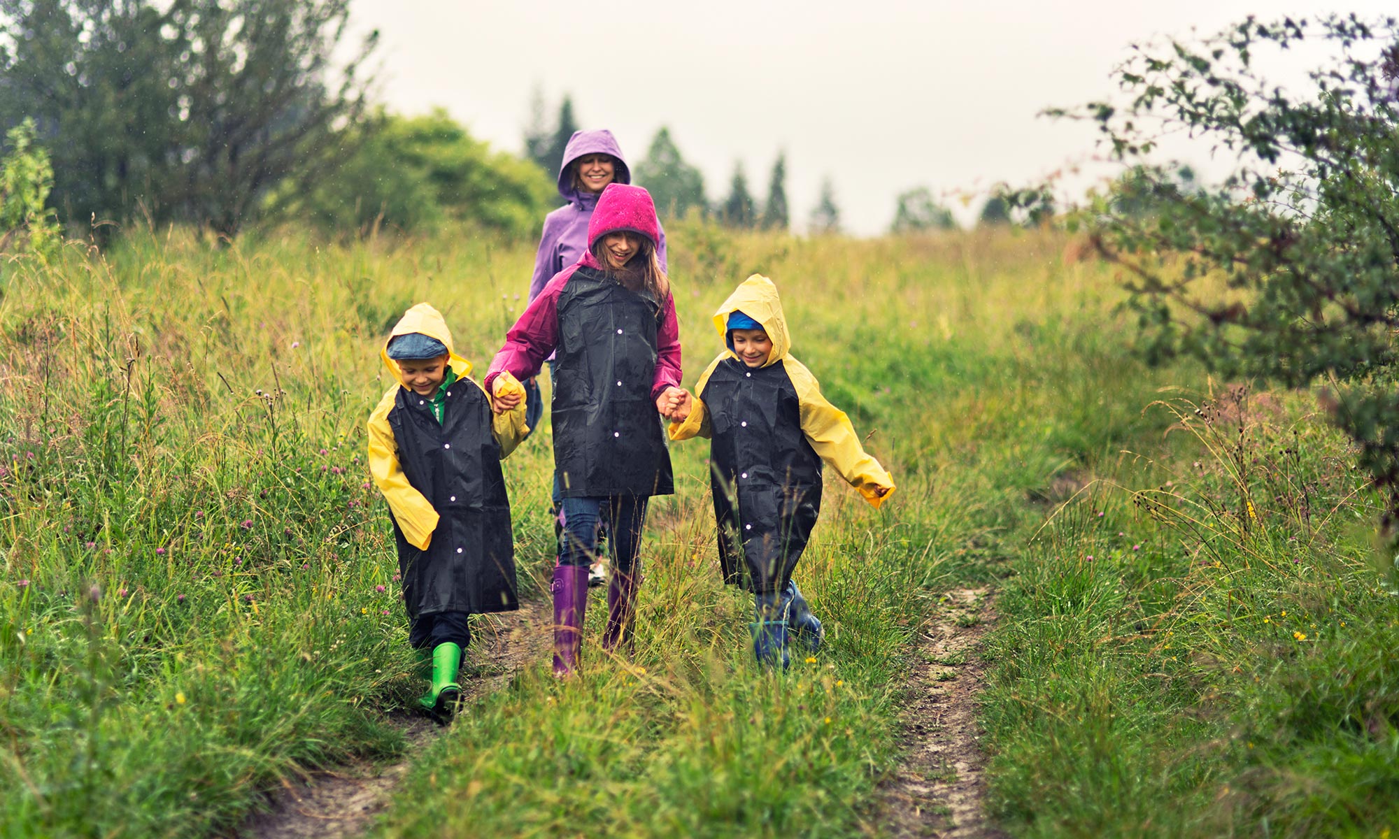 A family outdoors with raincoats on.