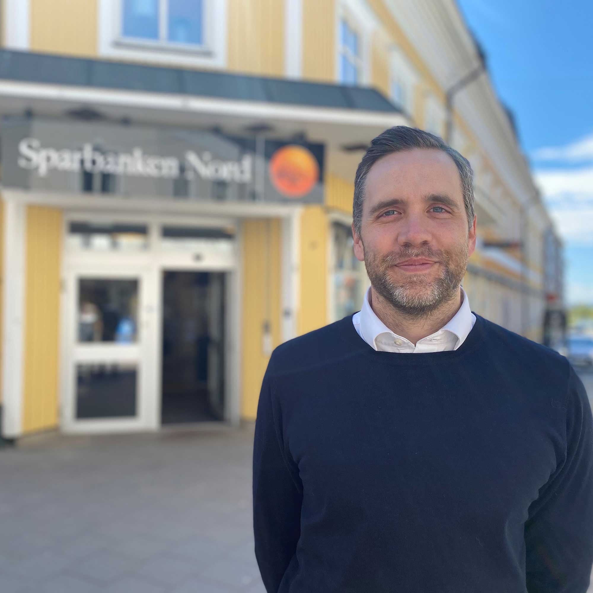 Man standing in front of house with sign Sparbanken Nord