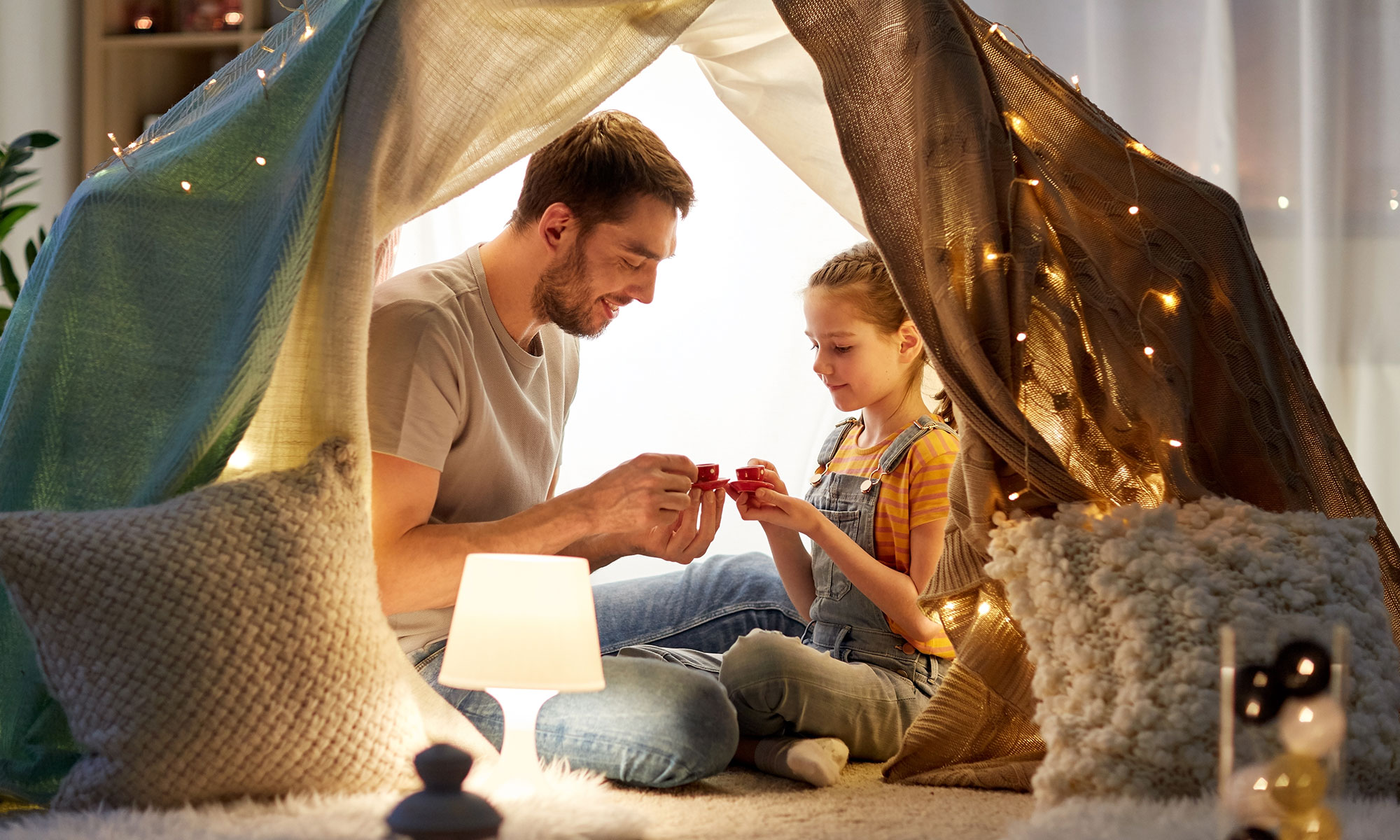 family playing tea party in kids tent at home