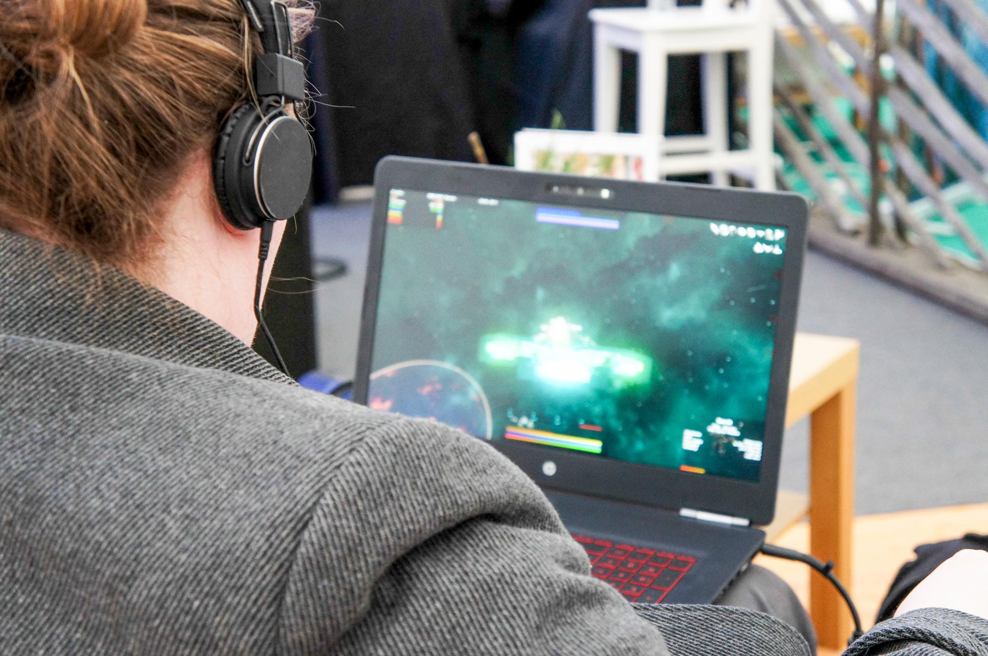 Kille som sitter med hörlurar framför en laptop och spelar spel.